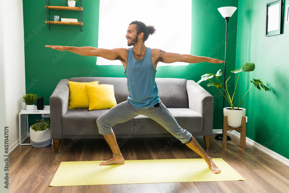 Naklejka premium Hispanic man smiling while doing yoga