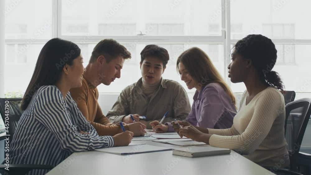 College friendship. Group of young multiethnic students studying together at campus library, making study project