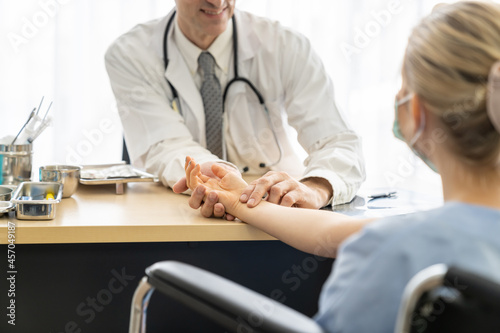 Senior man doctor examining the woman patient pulse with his hands. Healthcare and medical concept.