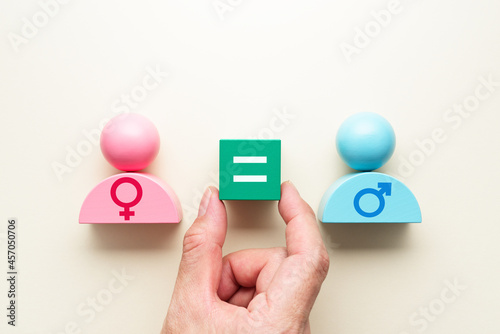 Gender equality. Hand putting equal sign block between female and male symbols.