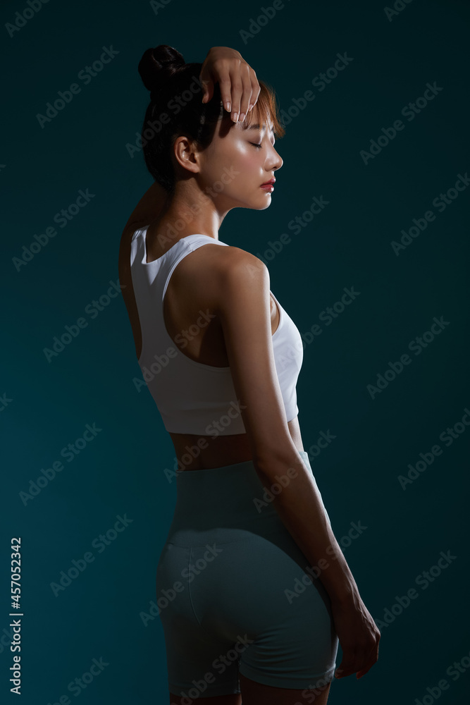 Fototapeta premium スポーツウェアを着た若い女性の陰影のあるポートレート