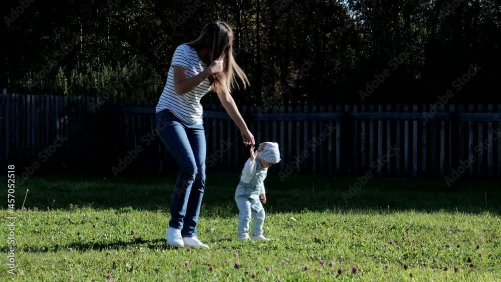 Young mother with her daughter running on the lawn Young mother with her daughter running on the lawn