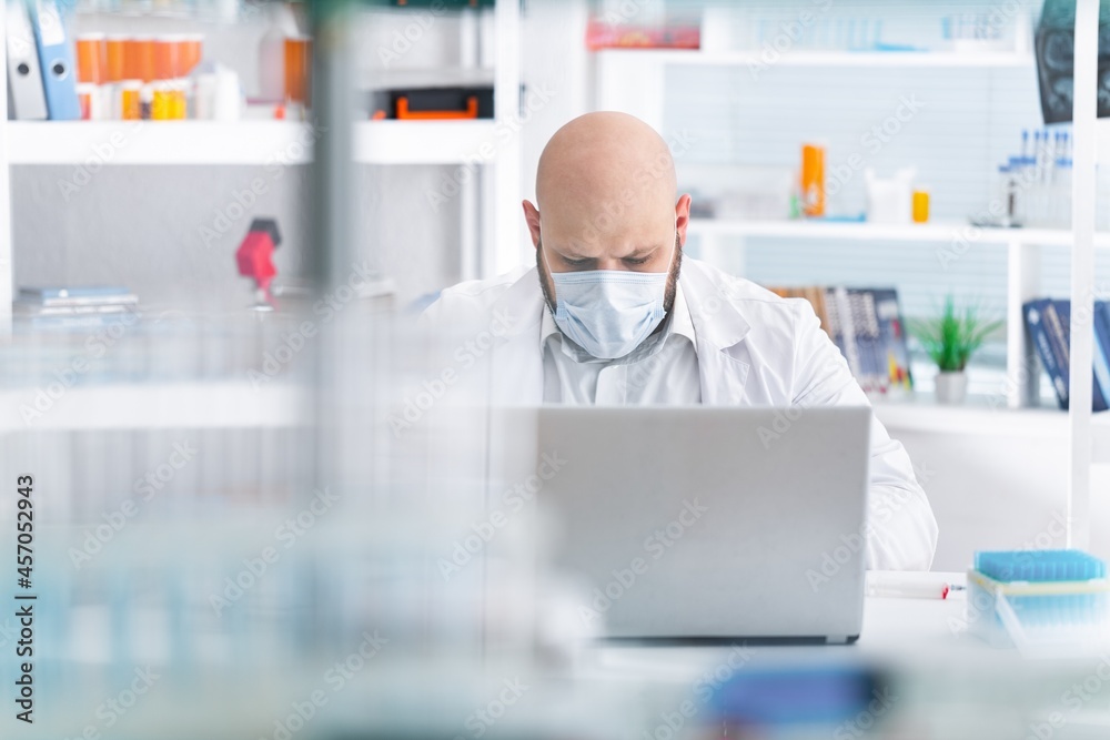 Male Scientist Working on a Computer with Display Showing Gene Editing Interface. Microbiologist is Rubber Gloves in a Bright Laboratory with Technological Equipment.