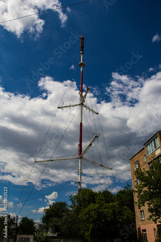 A TV tower on the background of the sky among residential buildings.