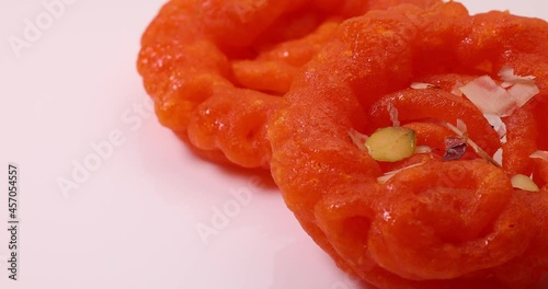 Deep fried all purpose flour batter dipped in sugar syrup sweet dessert red orange Jalebi jilapi Imarti on white background move slide rotate photo