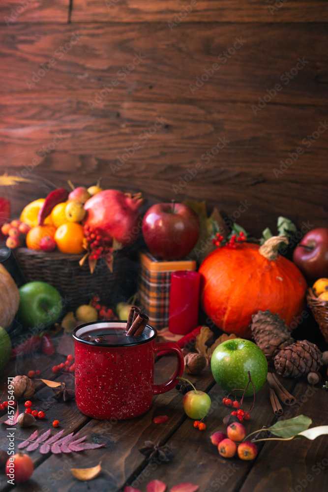 red mug with mulled wine. smoke comes from the mug. Cinnamon sticks stick out of the cup and a star of star anise floats. Fruits and spices are all around on a wooden table red mug with mulled wine. smoke comes from the mug. Cinnamon sticks stick out of the cup and a star of star anise floats. Fruits and spices are all around on a wooden table