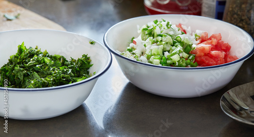 Prepared ingredients basil, green onions and tomatoes, chopped in salad bowls
