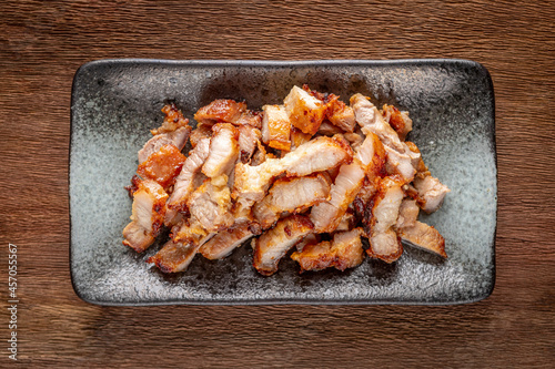 tasty slice fried pork in rectangular ceramic plate on rustic natural wood texture background, top view