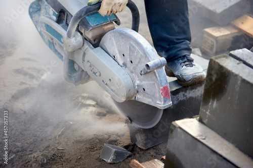 A worker with a circular saw cuts a curb stone close-up.