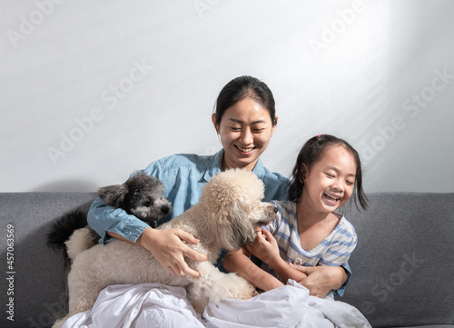 Photography Young beautiful mother and little cute daughter have fun playing with dogs on the home sofa