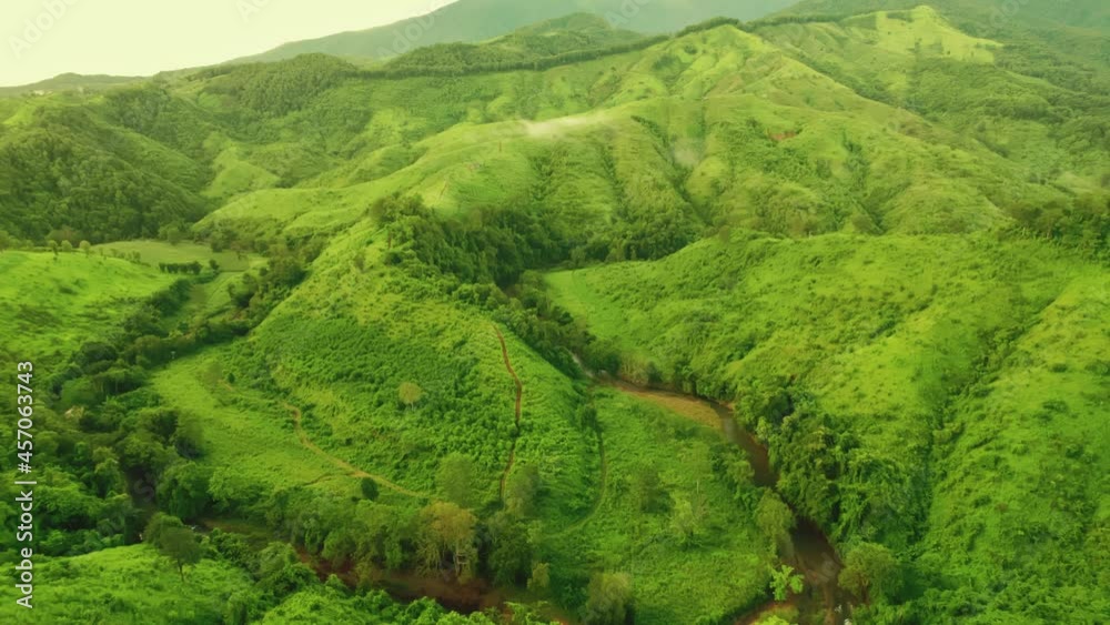 Aerial view drone shot of flowing fog waves on mountain tropical rainforest In the evening,Bird eye view image over the clouds Amazing nature background with clouds and mountain peaks.