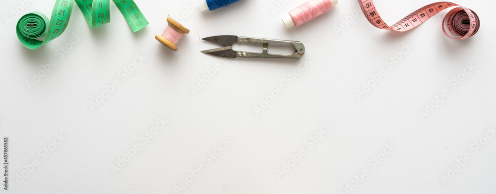 Panoramic view on sewing composition with threads, scissors, buttons, pins and other sewing accessories on white background. Long banner, top view, copy space, flat lay, mock up. Spase for text Panoramic view on sewing composition with threads, scissors, buttons, pins and other sewing accessories on white background. Long banner, top view, copy space, flat lay, mock up. Spase for text