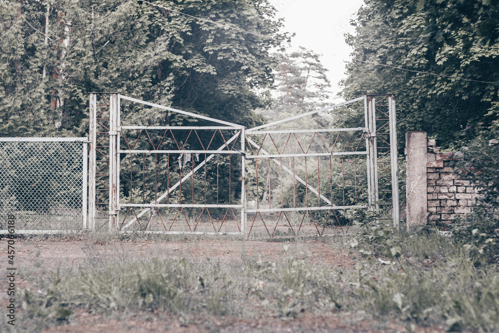 Old abandoned metal gate, on grassy forest road