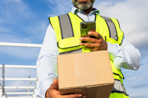 Anonymous workman with box browsing smartphone photo