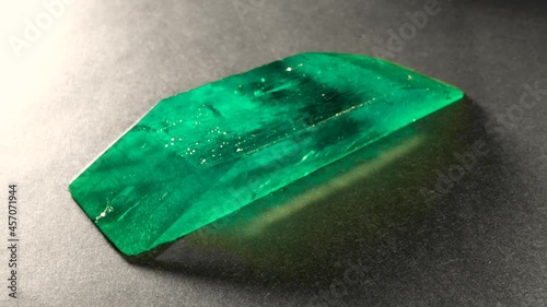Close up rotating filming of uncut emerald gem crystal jewellery. Rough precious minerals shots. Macro shooting of raw fine gemstone ready to be cut. Trinket jewelry fortune, green color stone edges. photo