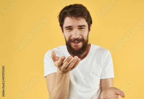 Cheerful bearded man on a yellow background gesturing with his hands