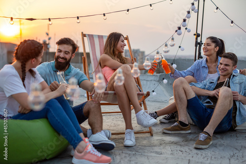 Happy friends toasting with drinks at a rooftop party photo