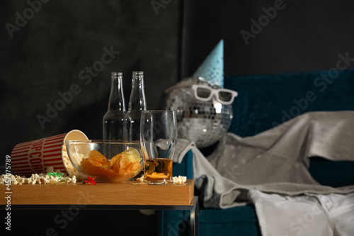 Photography Messy table with food leftovers near clothes on armchair in room after party