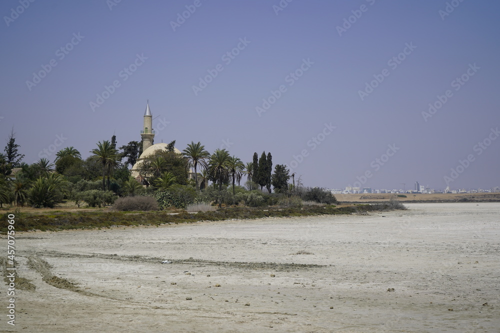 Larnaca, Cyprus, September 2021: Hala Sultan Tekke Mosque on the background of a salt lake. Dried up salt lake. Natural salt on the surface of the earth