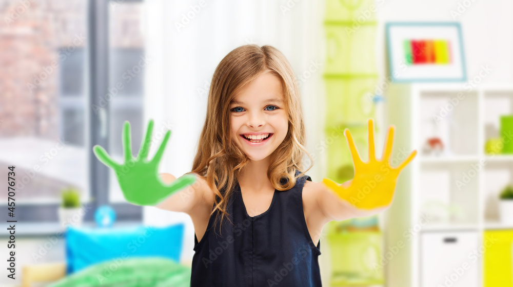 art, creativity and painting concept - happy smiling little girl showing painted hands over home room background art, creativity and painting concept - happy smiling little girl showing painted hands over home room background