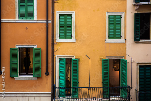 Ochre, yellow and cream houses with green shutters: a close-up of houses in Vicolo Tre Marchetti, Verona, Italy photo
