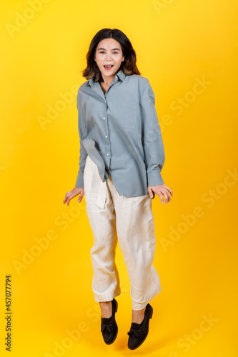 Lively Asian girl wearing casual long sleeve shirt and trousers enjoy exciting play of funny jump up and dance to stretch out and easy exercise for health refreshment show on cutout portrait