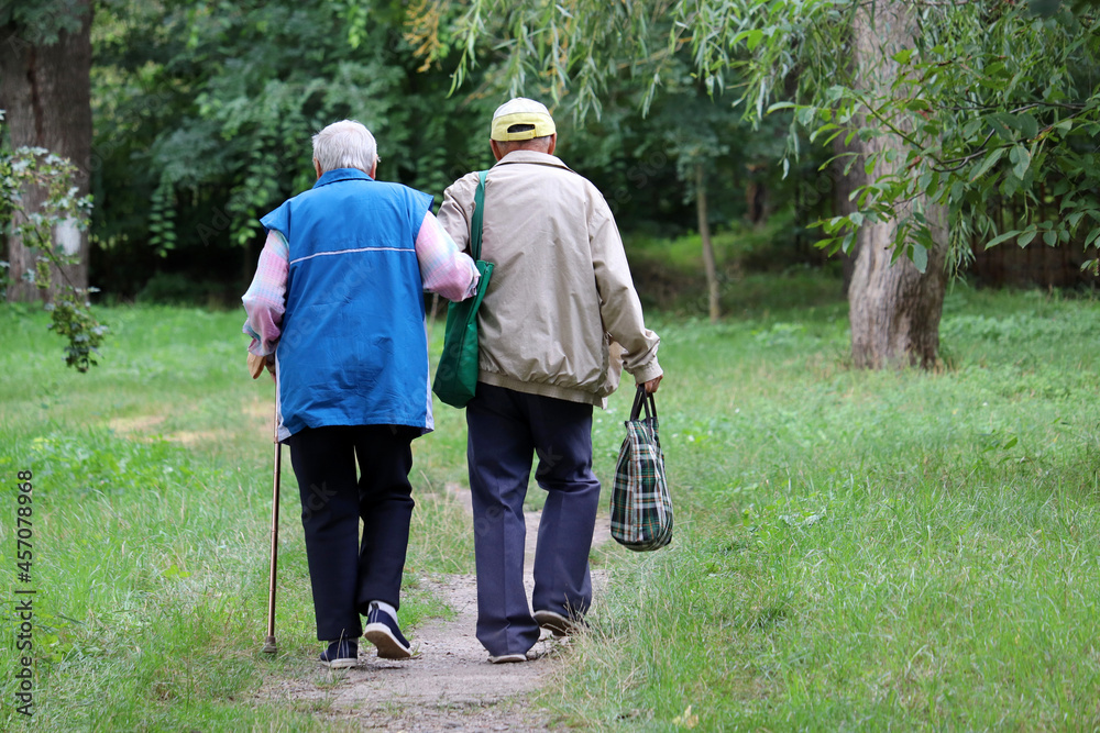 Elderly couple walking in a park holding hands. Old man holds woman ...