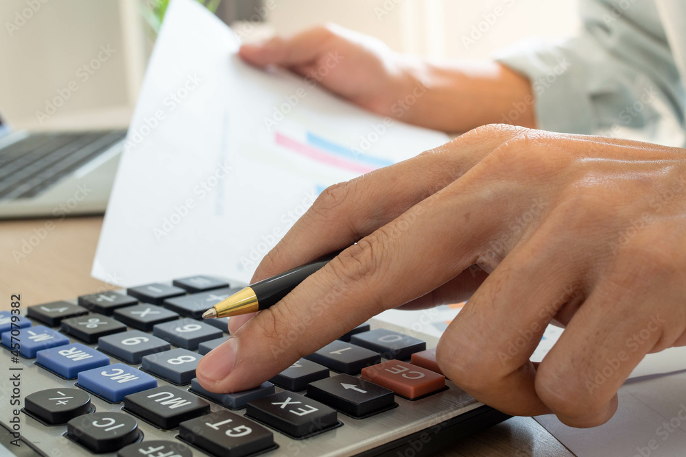 A man uses a calculator to calculate company profits from statistical graphs. Business men looking at charts, spreadsheets, bank accounts, statistics, economy, data analysis, stock exchange A man uses a calculator to calculate company profits from statistical graphs. Business men looking at charts, spreadsheets, bank accounts, statistics, economy, data analysis, stock exchange