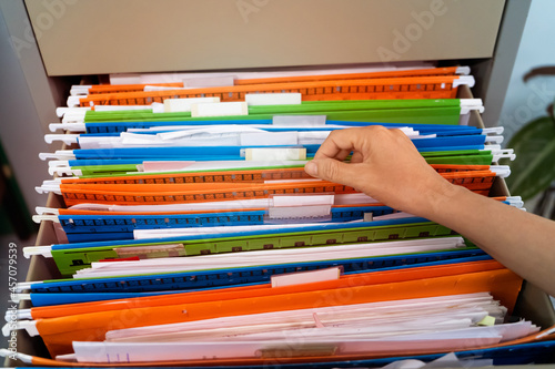 Woman's hand searching for documents at the filing cabinet.