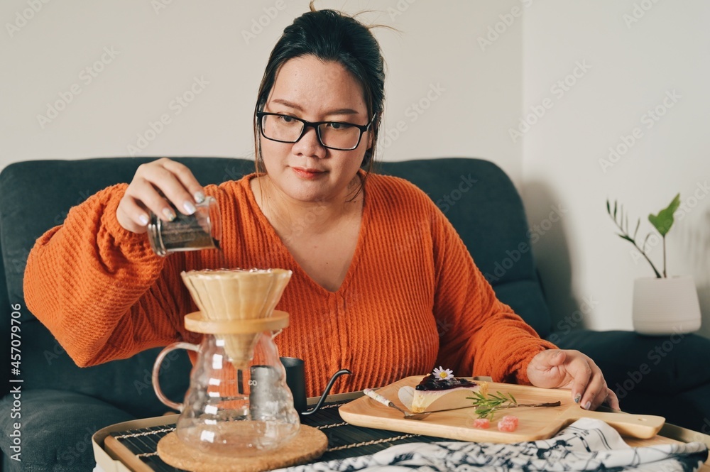 Asian woman pouring over coffee with dripper for brewing coffee at home. Enjoyed the bakery and coffee. Asian woman pouring over coffee with dripper for brewing coffee at home. Enjoyed the bakery and coffee.