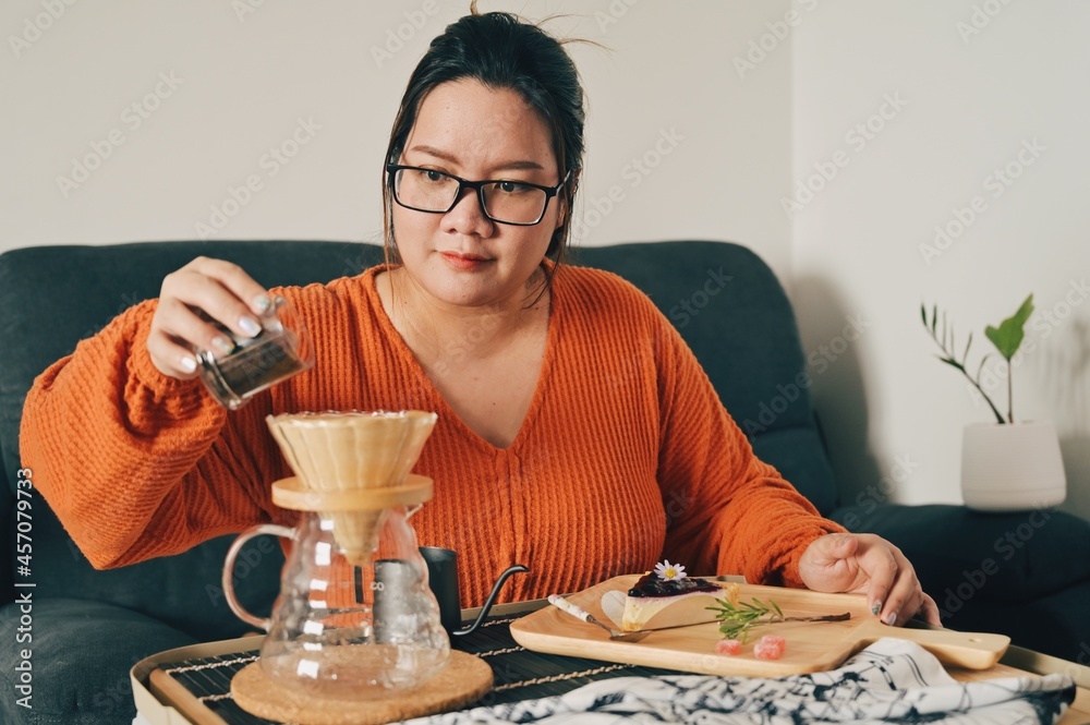 Asian woman pouring coffee beans into dripper Asian woman pouring coffee beans into dripper