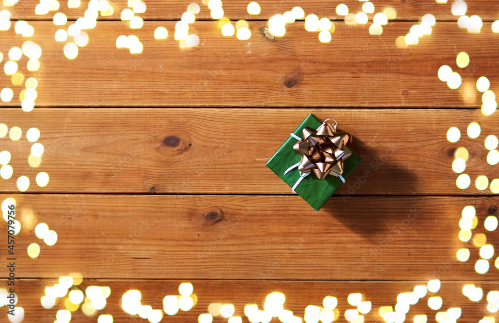 christmas, holidays and celebration concept - gift box on wooden boards from top over festive lights christmas, holidays and celebration concept - gift box on wooden boards from top over festive lights