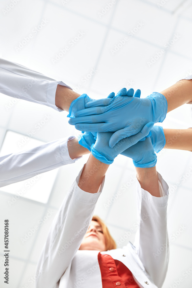 Fototapeta premium Hands in blue gloves covid, concept - creative team with hands on top of each other. Diverse team putting their hands together. One for all gesture in gloves. Covid-19 concept.