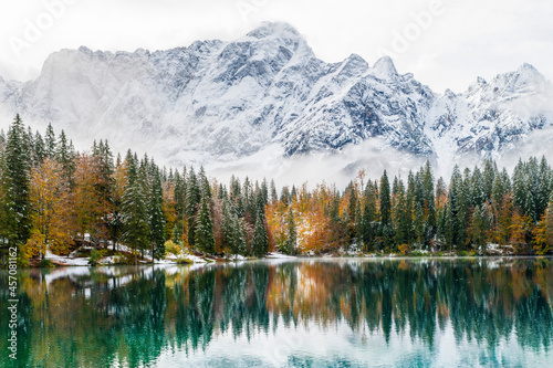 Fototapeta Naklejka Na Ścianę i Meble -  Between autumn and winter. Warm and cold reflections of snow on Lake Fusine.