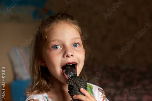 a little girl eats black ice cream, her mouth and teeth are black