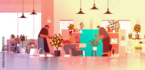 mix race businesspeople taking care of potted plants in office gardening concept horizontal