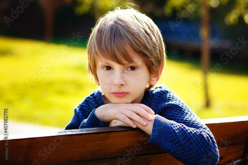 Close-up portrait of a beautiful red-haired boy with a very serious look. A sad expression on his face. Outdoor, copy space.