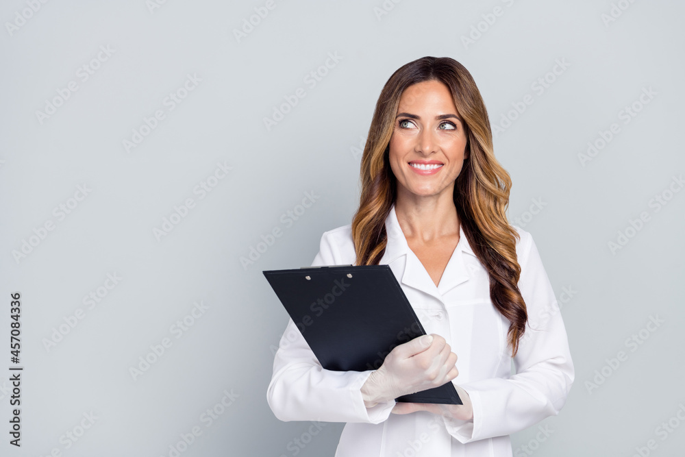 Portrait of attractive cheery woman doc holding paper document thinking copy space isolated over grey pastel color background Portrait of attractive cheery woman doc holding paper document thinking copy space isolated over grey pastel color background