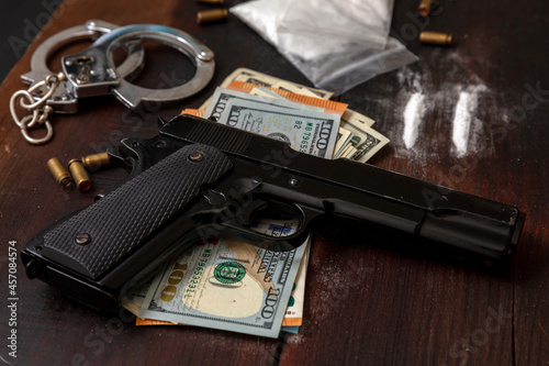 Fotografi Drugs smuggling and trafficking, Handcuffs, pistol money and cocaine on wooden t