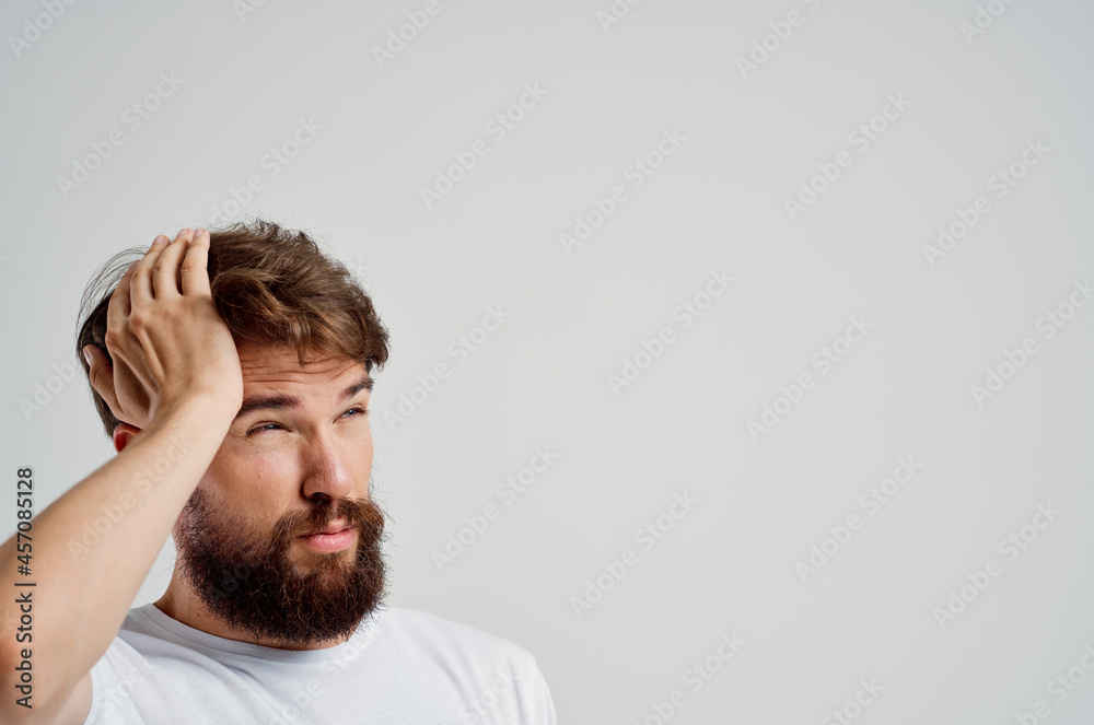 man in a white t-shirt headache migraine problems light background
