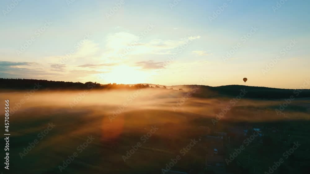 Beautiful sunset over the forest. Fog spreads through a small village. A flying air circle can be seen on the horizon. Orange sunset and light fog moving Beautiful sunset over the forest. Fog spreads through a small village. A flying air circle can be seen on the horizon. Orange sunset and light fog moving