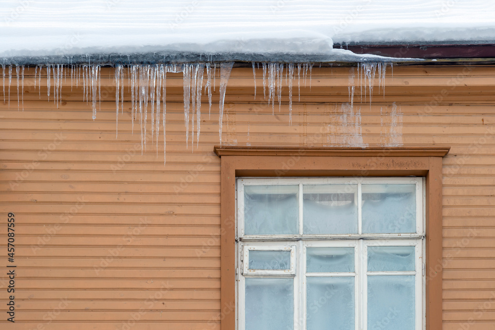 Sharp icicles hanging on the edge of the roof. Melting snow forms icicle. Sharp icicles hanging on the edge of the roof. Melting snow forms icicle.