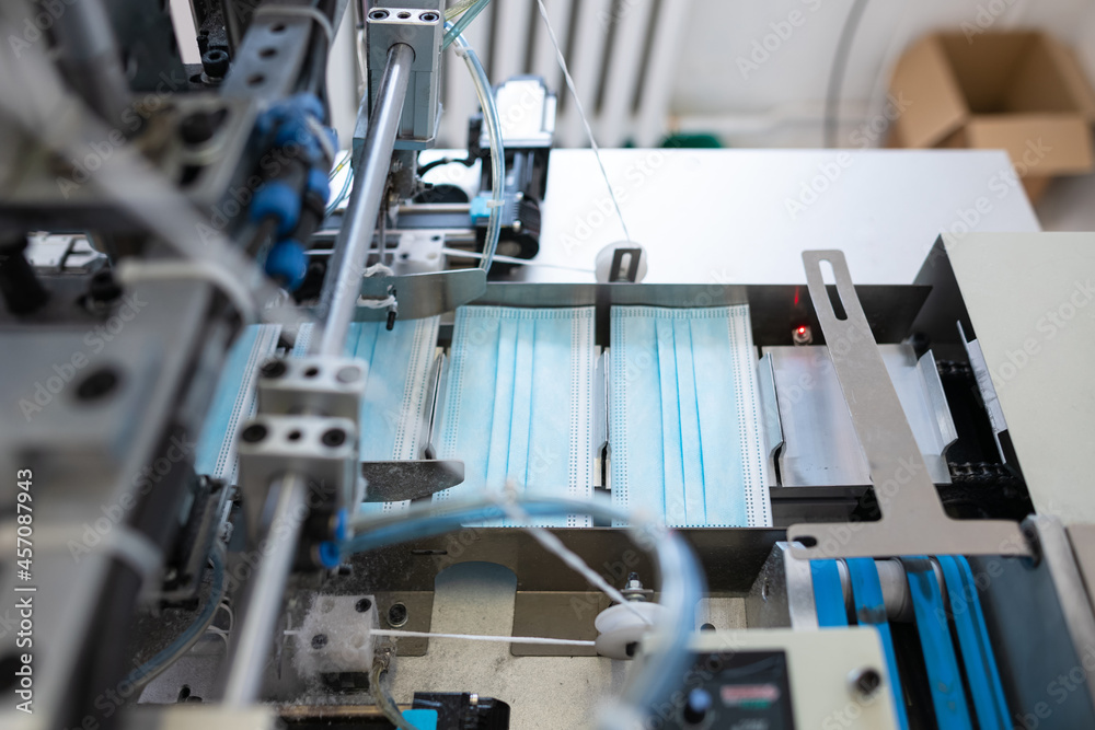 Closeup process of medical face masks being made in a factory. Automated machinery making respiratory medical masks in large quantities. Closeup process of medical face masks being made in a factory. Automated machinery making respiratory medical masks in large quantities.