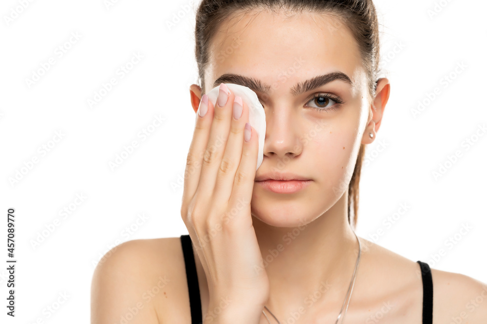 beautiful teen girl cleans her face with cotton pad