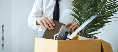 Business man employee packing notebook and picking up personal belongings into brown cardboard box