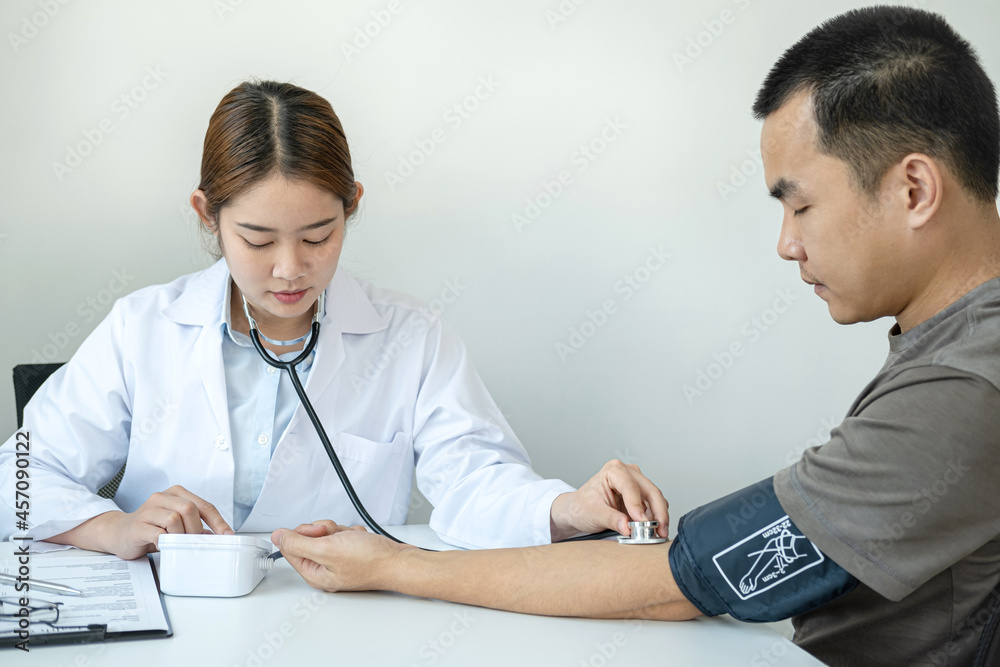 Doctor is checking blood pressure for the patient and using stethoscope to listening heartbeat Doctor is checking blood pressure for the patient and using stethoscope to listening heartbeat
