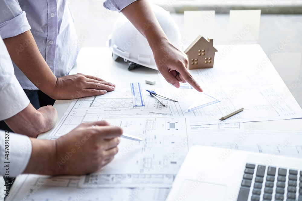 Team of engineering or architect meeting and discussing on blueprint and building model while checking information on sketching for architectural project Team of engineering or architect meeting and discussing on blueprint and building model while checking information on sketching for architectural project