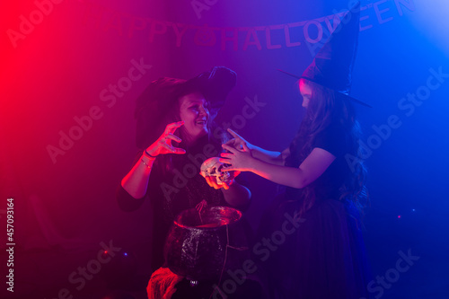 Two halloween witches making a potion and conjure in halloween night. Magic, holidays and mystic concept.