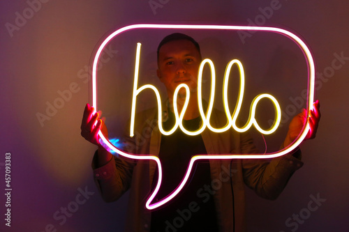 Handsome young man holding pink and yellow neon sign hello. Trendy style. Neon sign. Custom neon. Home decor.