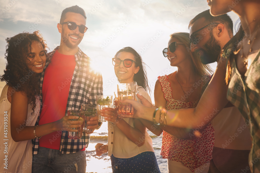 Group of friends with drinks having fun near river at summer party Group of friends with drinks having fun near river at summer party